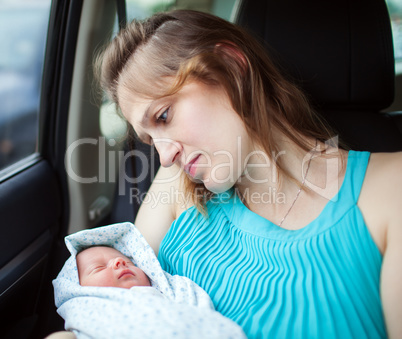 Woman holding newborn baby sitting in the car