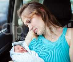 Woman holding newborn baby sitting in the car