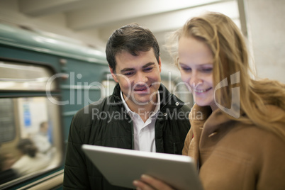 Happy young people with touch pad in subway