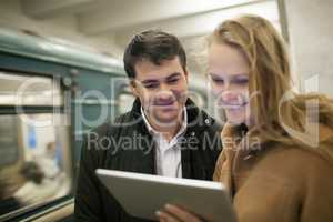 Happy young people with touch pad in subway
