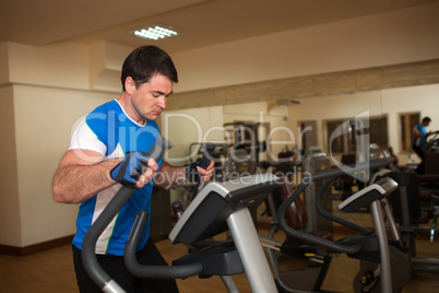 Man exercising on elliptical machine in gym