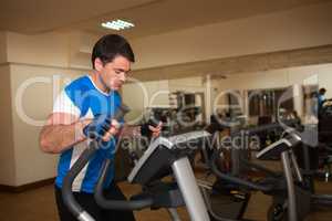 Man exercising on elliptical machine in gym