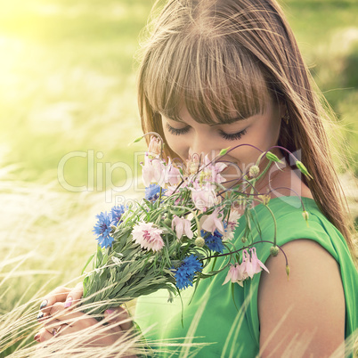 Young sensual girl smelling a bouquet of wildflowers