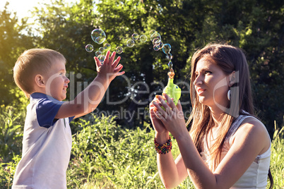 Boy playing catch soap bubbles outdoors