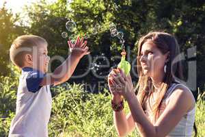 Boy playing catch soap bubbles outdoors