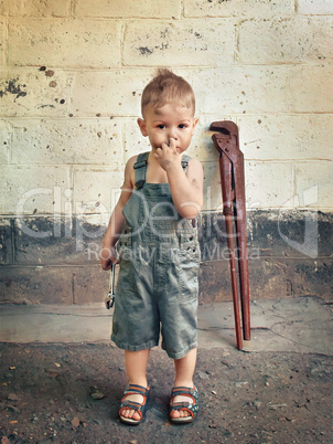 little boy with a wrench standing at the wall