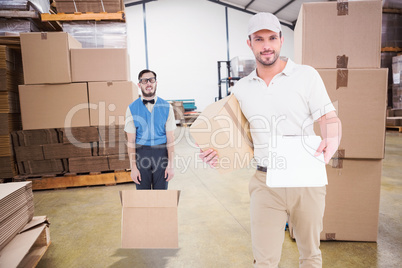 Composite image of delivery man with cardboard box showing clipb