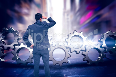 Composite image of businessman standing hand on hip