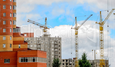 Cranes and building construction on the background of clouds