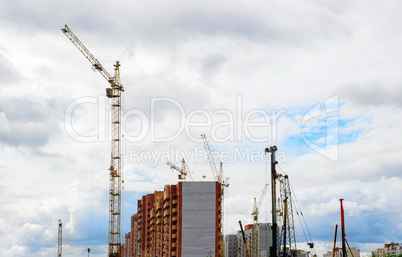 Cranes and building construction on the background of clouds