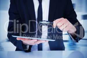 Composite image of businessman looking at his tablet through mag