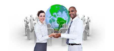 Composite image of business colleagues holding plant and looking