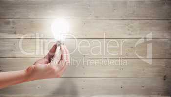 Composite image of hand holding light bulb