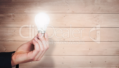 Composite image of hand holding light bulb