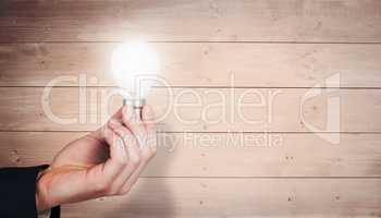 Composite image of hand holding light bulb