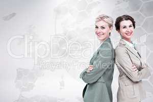 Composite image of serious businesswomen standing back on back