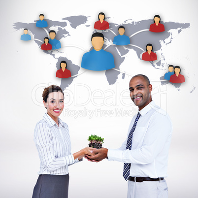 Composite image of business colleagues holding plant and looking