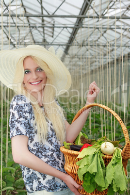 Hübsche Frau trägt einen Korb mit Gemüse auf dem Arm
