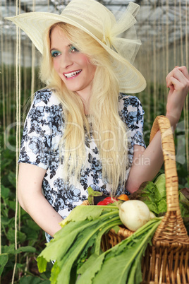 Glückliche blonde Frau trägt einen Korb mit Gemüse