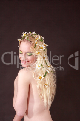 Glückliche nackte Frau mit Blumen in Ihrem blonden Haar
