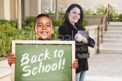Boy Holding Back To School Chalk Board with Teacher Behind
