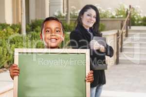 Boy Holding Blank Chalk Board on Campus with Teacher Behind