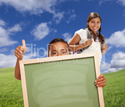 Students with Thumbs Up in Field Holding Blank Chalk Board