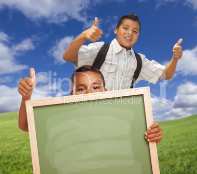 Hispanic Students with Thumbs Up in Grass Field Holding Blank Chalk Board.