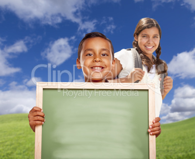 Hispanic Boy and Girl In Field Holding Blank Chalk Board