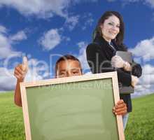 Young Boy with Blank Chalk Board, Teacher Behind on Grass