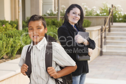 Hispanic Boy with Backpack on School Campus and Teacher Behind
