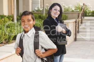 Hispanic Boy with Backpack on School Campus and Teacher Behind