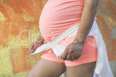 Pregnant women in front of orange wall.