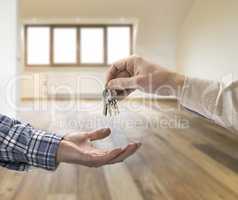 Realtor giving house key to buyer in empty room