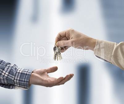 Man is handing a house key to a other man in the shape of the ho
