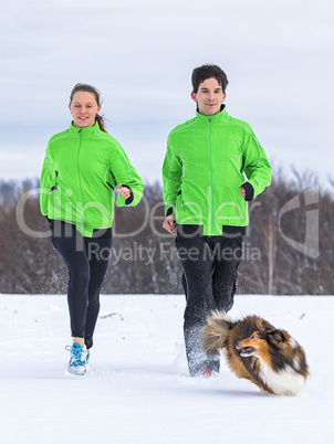 junges Paar joggt mit Hund im Winter