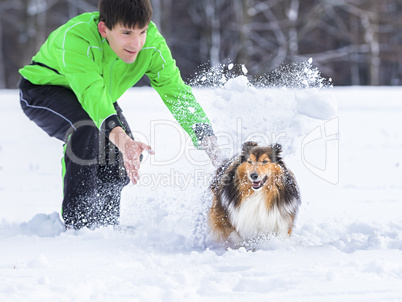 junger Mann spielt mit Hund im Schnee