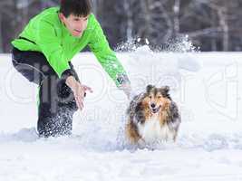 junger Mann spielt mit Hund im Schnee