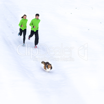 junges Paar joggt mit Hund im Schnee