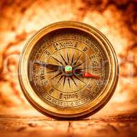 Vintage compass lies on an ancient world map.