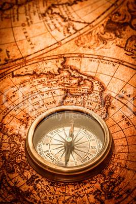 Vintage compass lies on an ancient world map. Vintage compass lies on an ancient world map.
