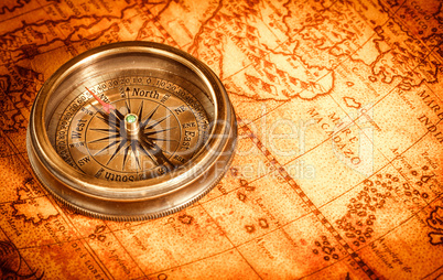 Vintage compass lies on an ancient world map.