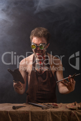 crazy man in an apron with a knife in his hand on a gray background