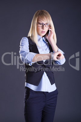 blond girl talking on the phone on a gray background