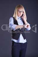 blond girl talking on the phone on a gray background
