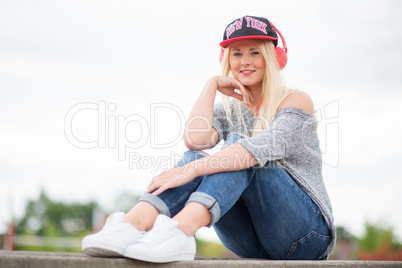 Blondes Mädchen mit Kappe und Kopfhörer