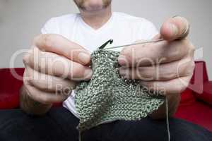 Closeup of a man knitting a scarf