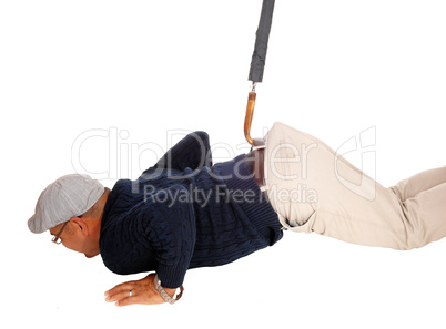 Man lying on floor pulled up with umbrella.