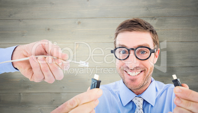 Composite image of geeky businessman holding two cables