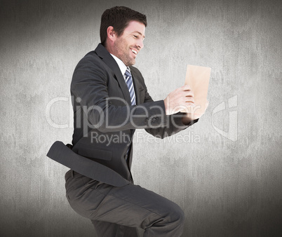Composite image of businessman lying on the floor reading a book